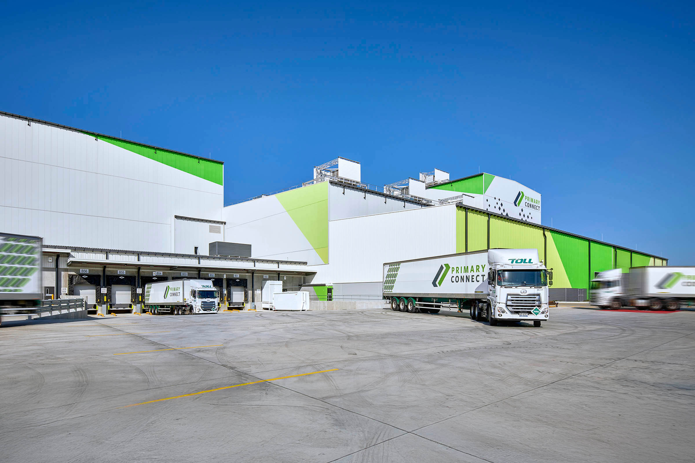 001-Hero-image-trucks-pulling-into-facility-clear-sky-white-and-green-branding-Woolworths-MoRDC-Richard-Crookes-Constructions-Industrial (1)